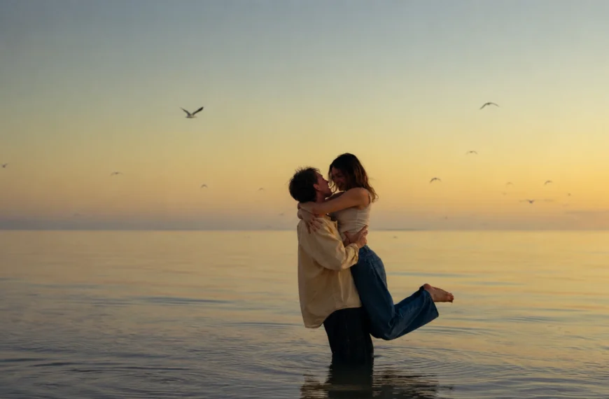 Marriage Goals | Romantic couple embracing in shallow water at sunset, with calm sea views, golden sky and birds flying in the background.