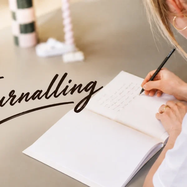 Journaling | Young Sri Lankan woman writing in a journal by a window with a cup of tea, practising journaling to reduce stress, organise her thoughts, and improve mental wellbeing.