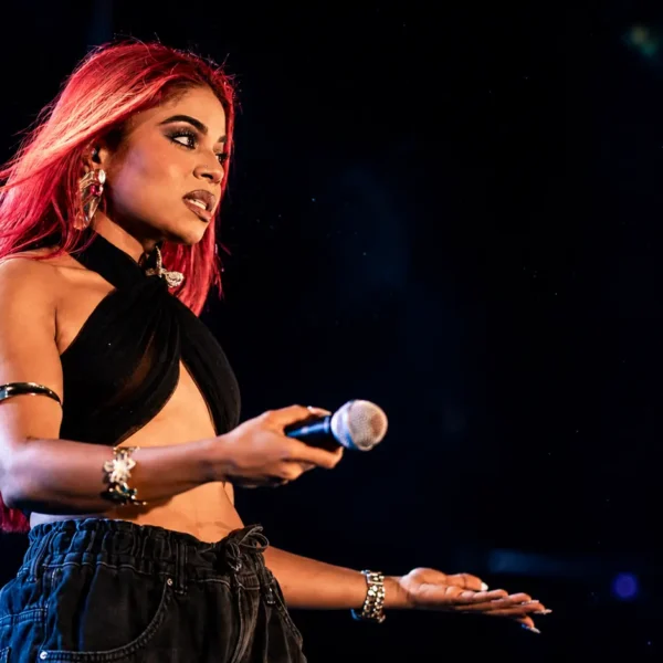Hate comments | **Alt Text:** Sri Lankan female singer performing on stage with a microphone under blue and red concert lights, illustrating the emotional impact of online hate and negative social media comments.