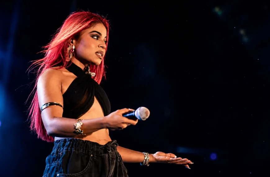 Hate comments | **Alt Text:** Sri Lankan female singer performing on stage with a microphone under blue and red concert lights, illustrating the emotional impact of online hate and negative social media comments.