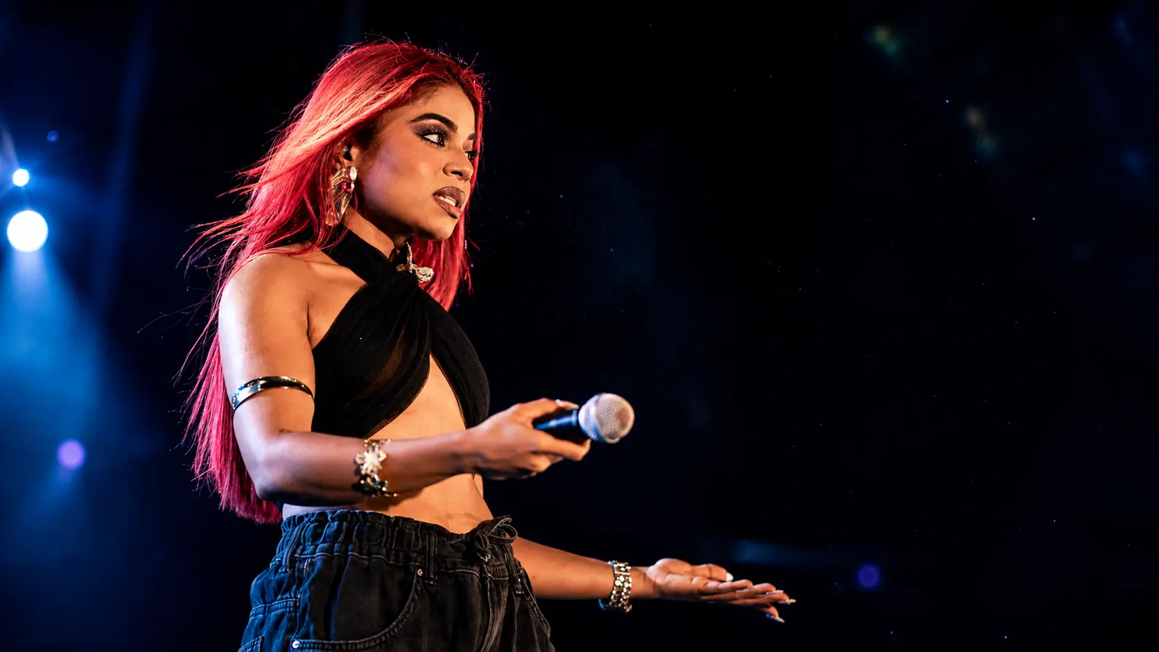 Hate comments | **Alt Text:** Sri Lankan female singer performing on stage with a microphone under blue and red concert lights, illustrating the emotional impact of online hate and negative social media comments.